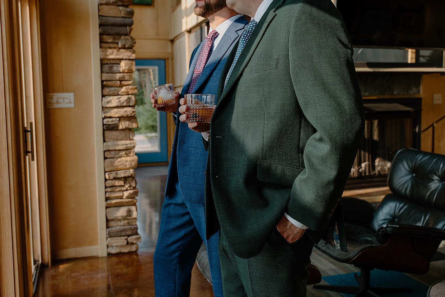 two men hold whiskey and look at window at Herbster WI Elopement