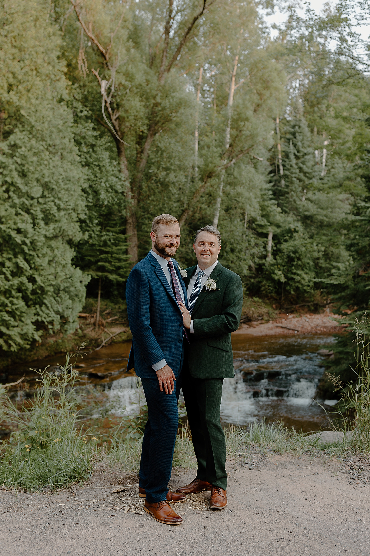 men in earth tone suit next to rushing river by Minnesota elopement photographer