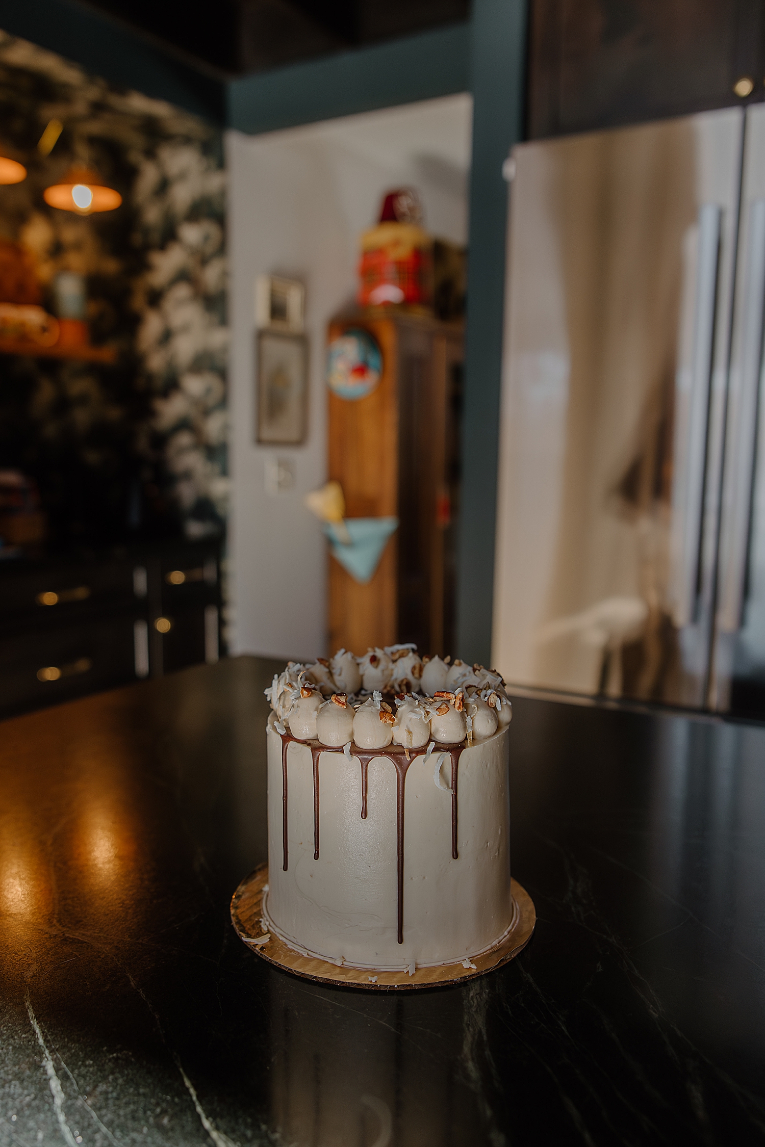 tall white cake with chocolate drip on countertop by Samantha Burke Photography