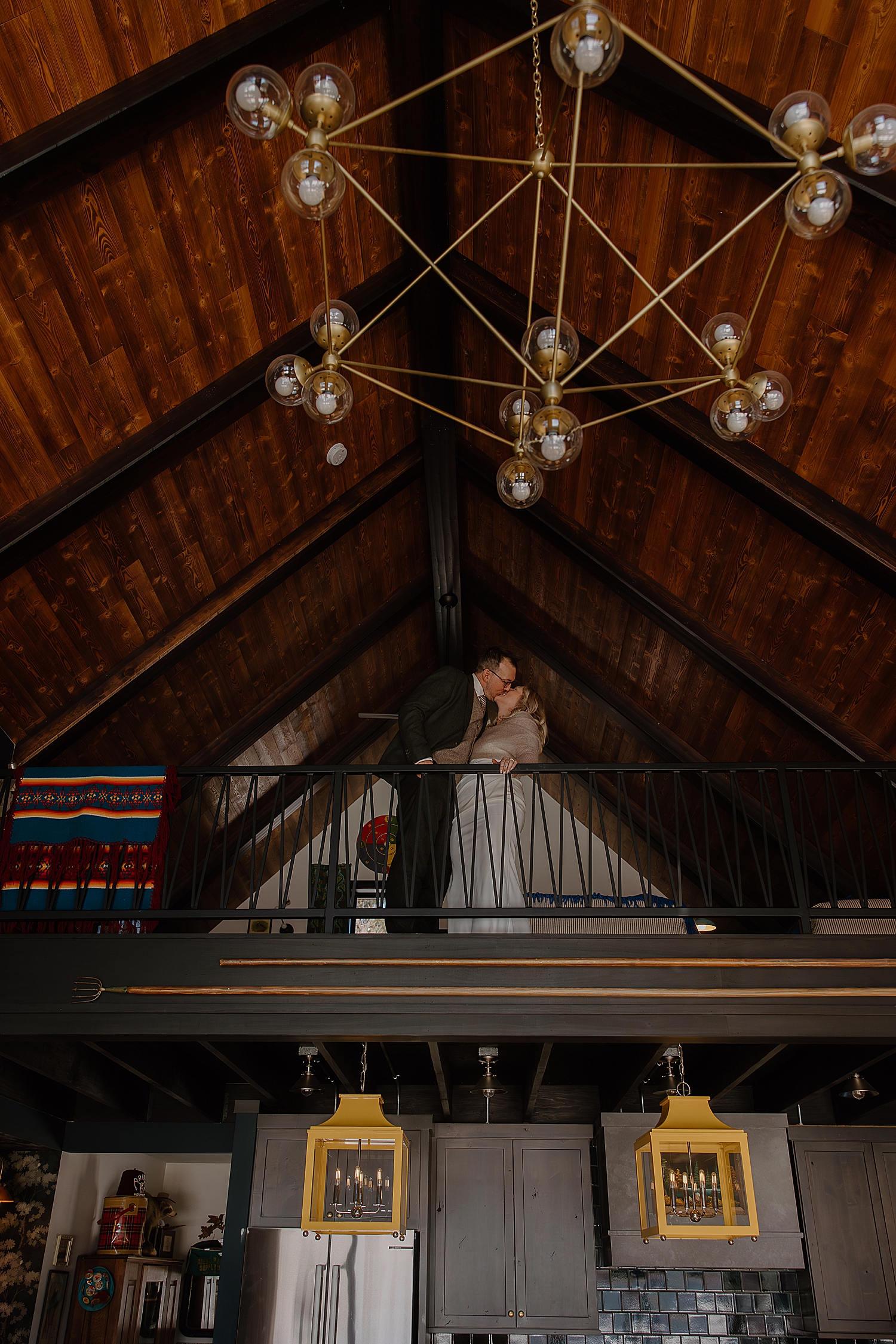 man and woman kiss over loft railing for airbnb elopement