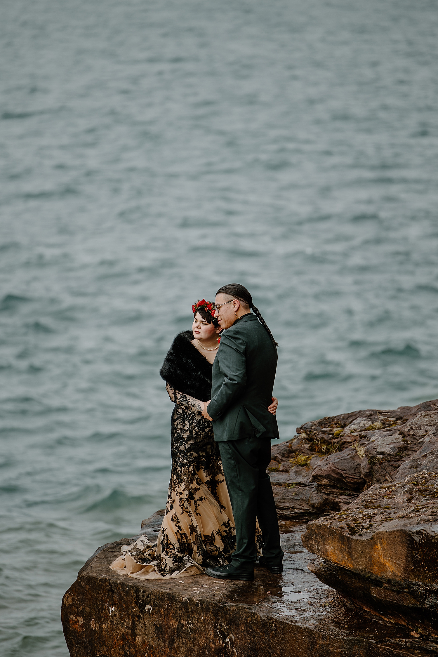 man with long braid holds new wife on cliffside by Samantha Burke Photography