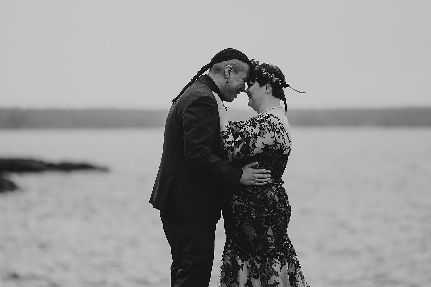 man and woman touch foreheads overlooking water for Beltane Elopement