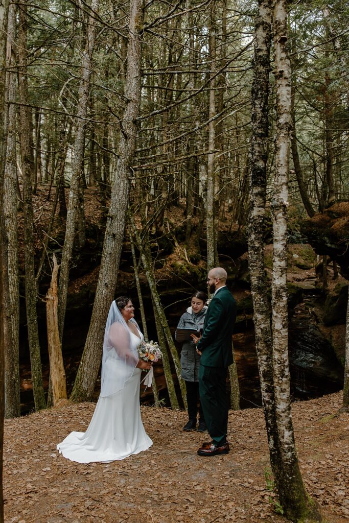couple stand together for ceremony under trees by Minnesota elopement photographer