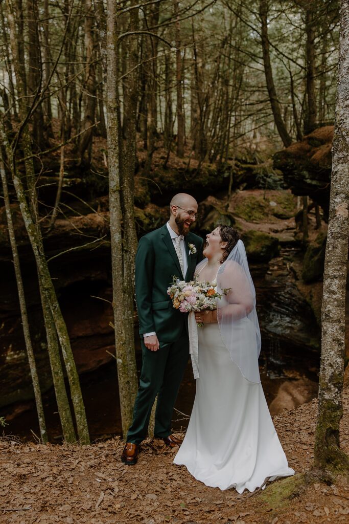 newlyweds laugh together under the trees for Intimate Ceremony at Houghton Falls