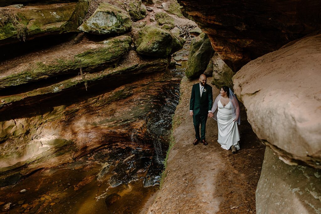 bride and groom walk next to creek by Minnesota elopement photographer