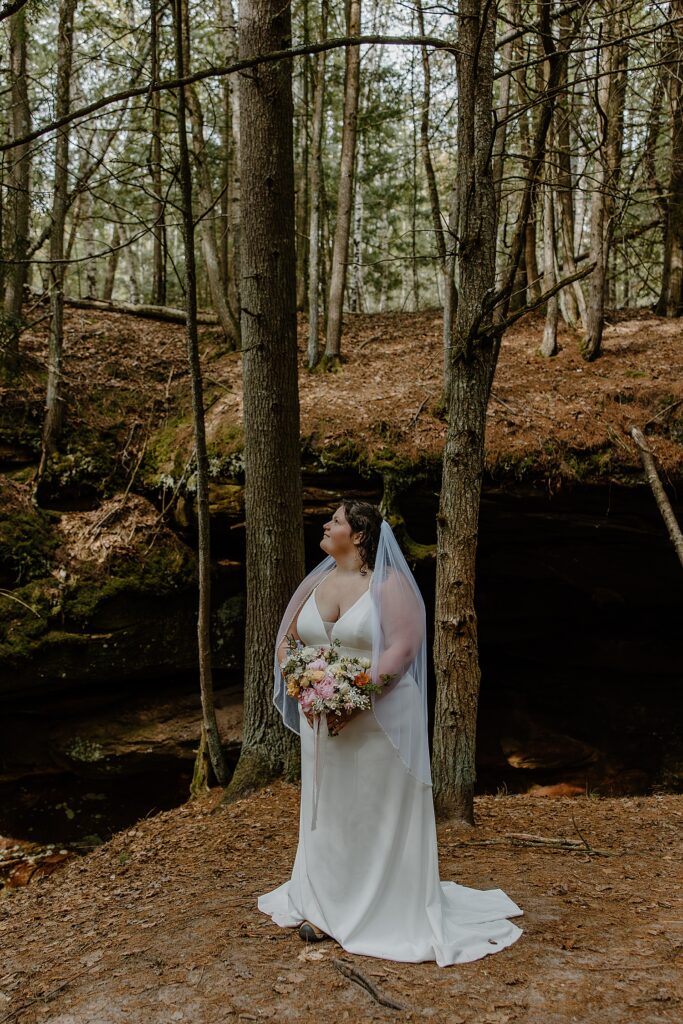 bride looks up at sky in forest by Samantha Burke Photography
