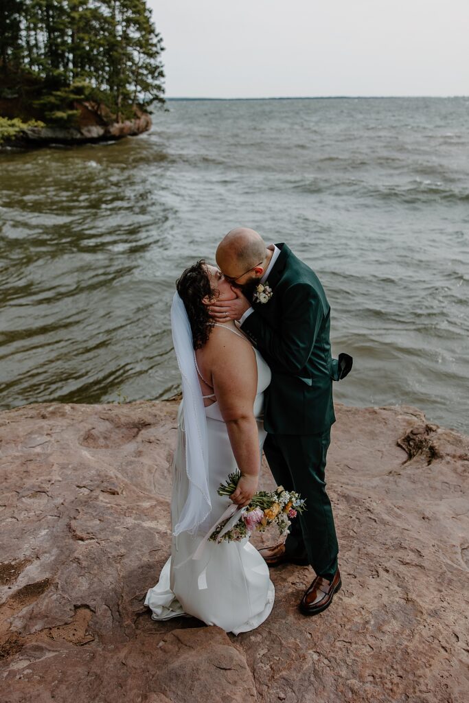 man cups woman's face as he leans in to kiss her by Minnesota elopement photographer