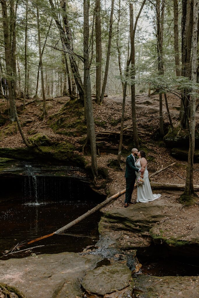 groom kisses his new wife next to small waterfall by Samantha Burke Photography
