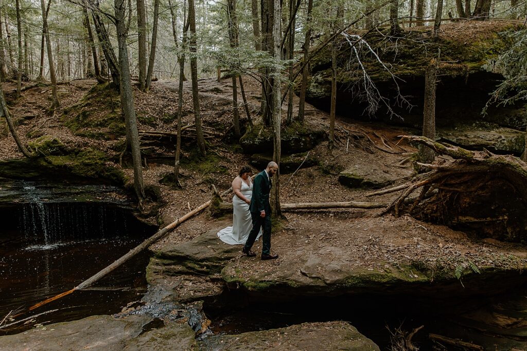 husband leads new wife through forest at Intimate Ceremony at Houghton Falls