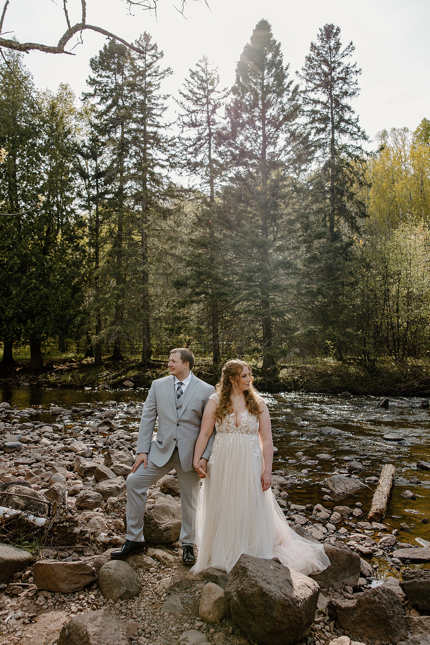 newlyweds stand in front of creek during the best time to elope at gooseberry falls state park