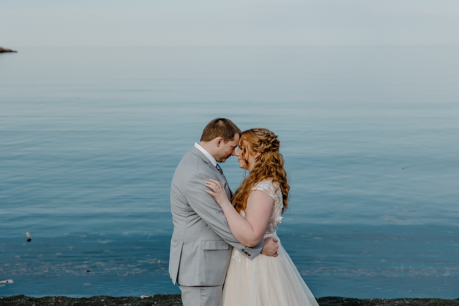 newlyweds stand close in front of water by Minnesota Elopement Photographer