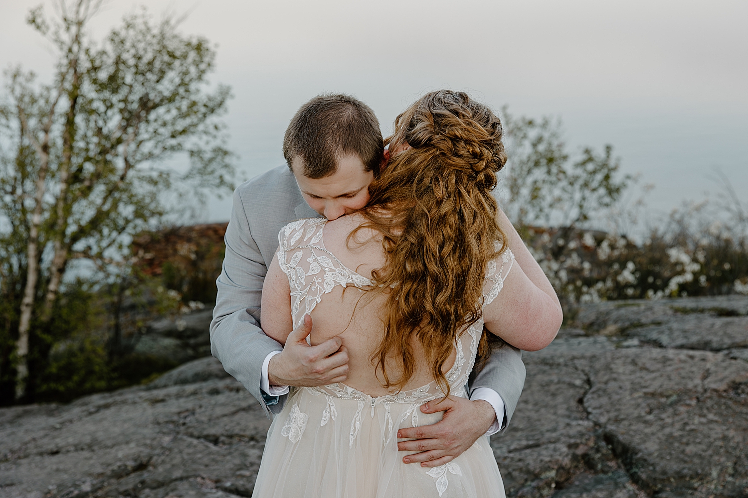 man hugs his new wife and kisses her shoulder by Samantha Burke Photography