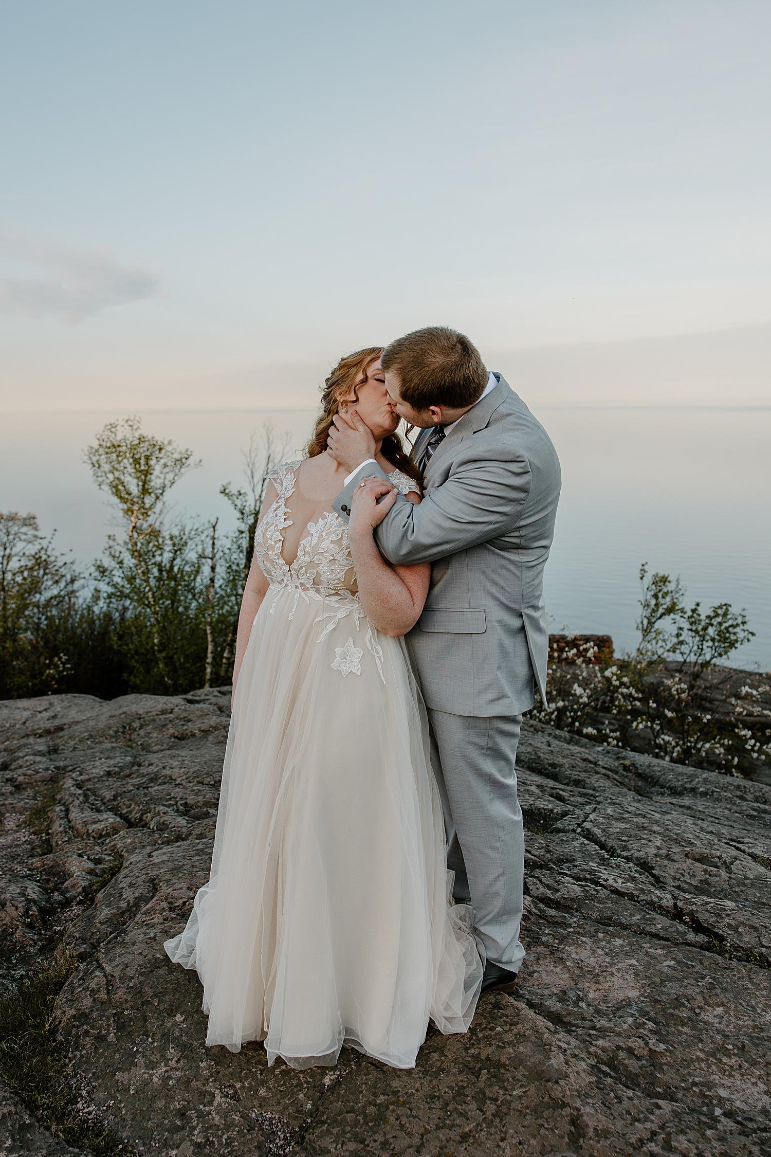 redhead bride and groom in gray suit on cliff by Samantha Burke Photography