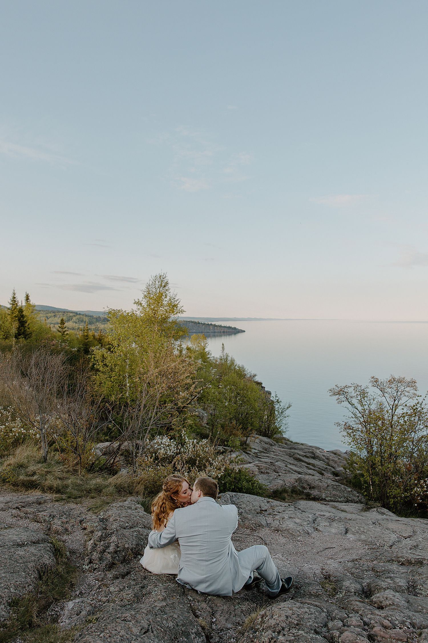 newlyweds sit together on cliffside overlooking North Shore by Samantha Burke Photography