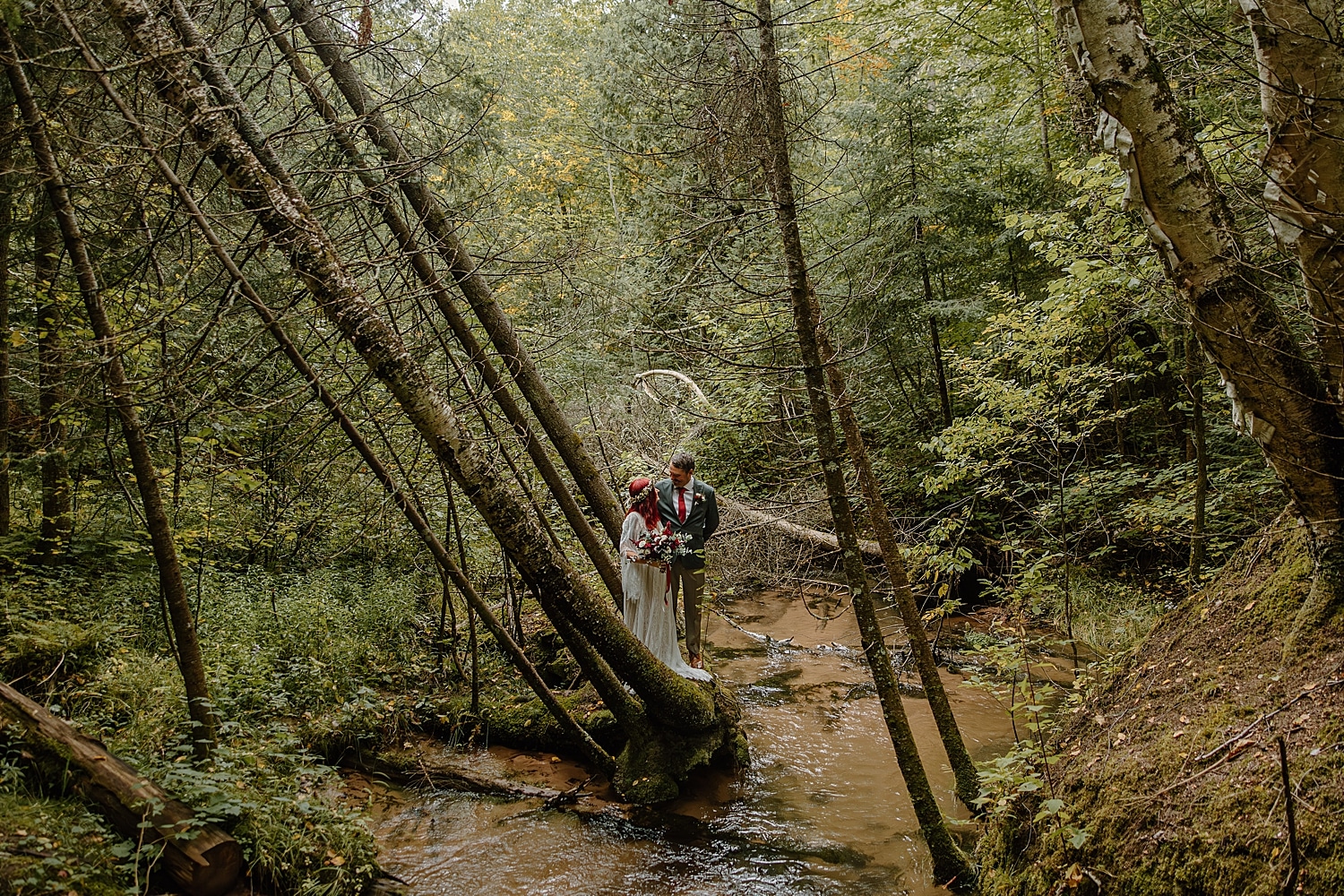 man looks lovingly at his new bride under forest trees by Samantha Burke Photography