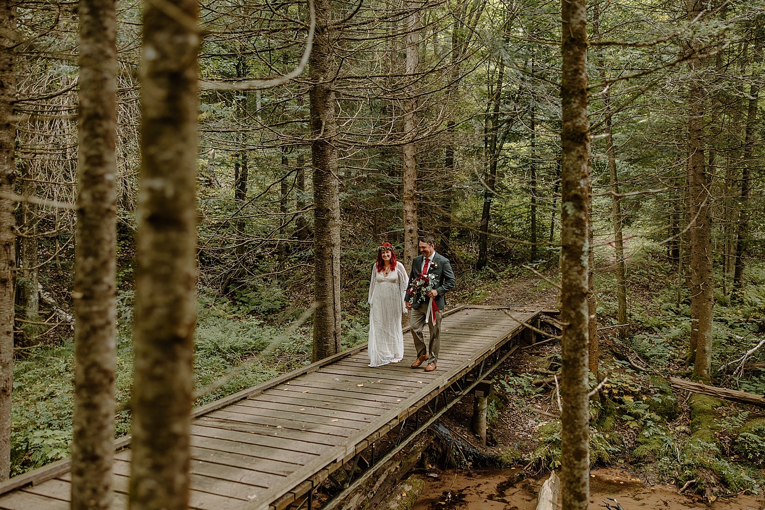 man and woman walk across wooden bridge by Samantha Burke Photography