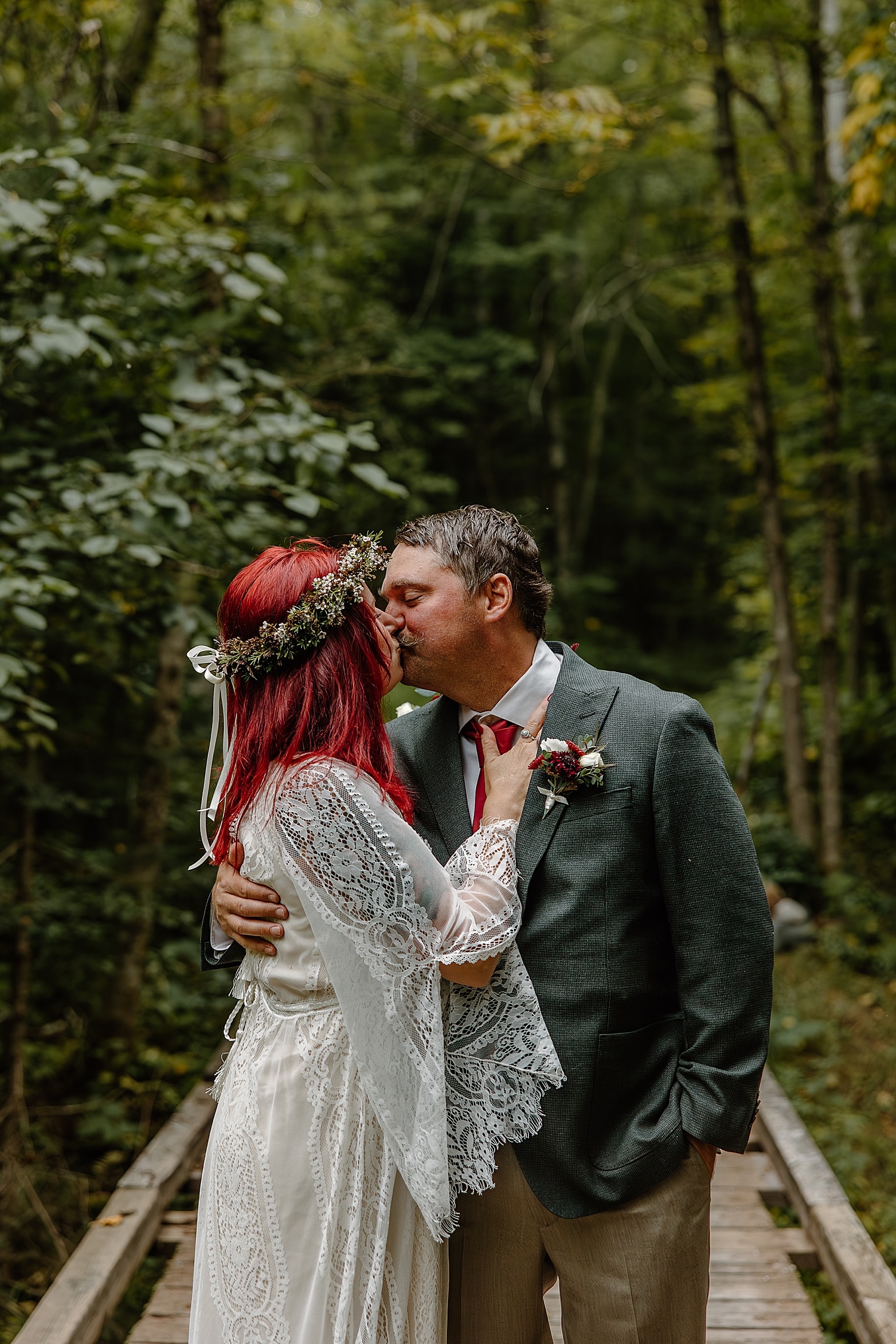 newlyweds share a kiss under big green trees by Minnesota wedding photographer