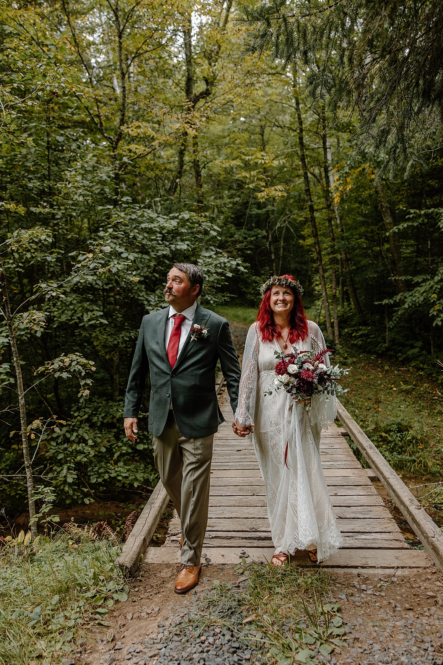 newlyweds with vibrant hair and tie color walk across wooden bridge by Minnesota wedding photographer