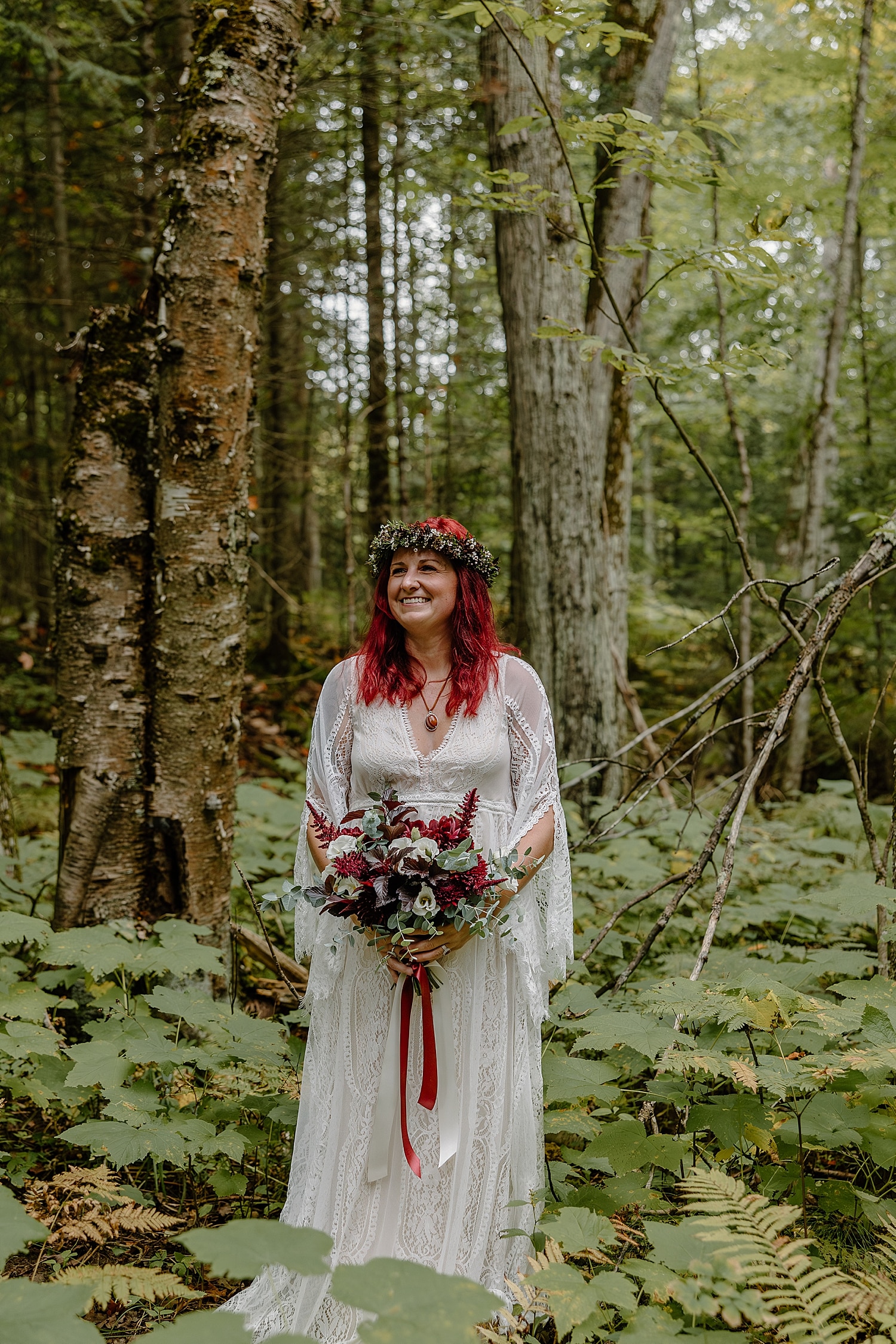 bride with vibrant red hair stands under trees for Wisconsin Beach Elopement