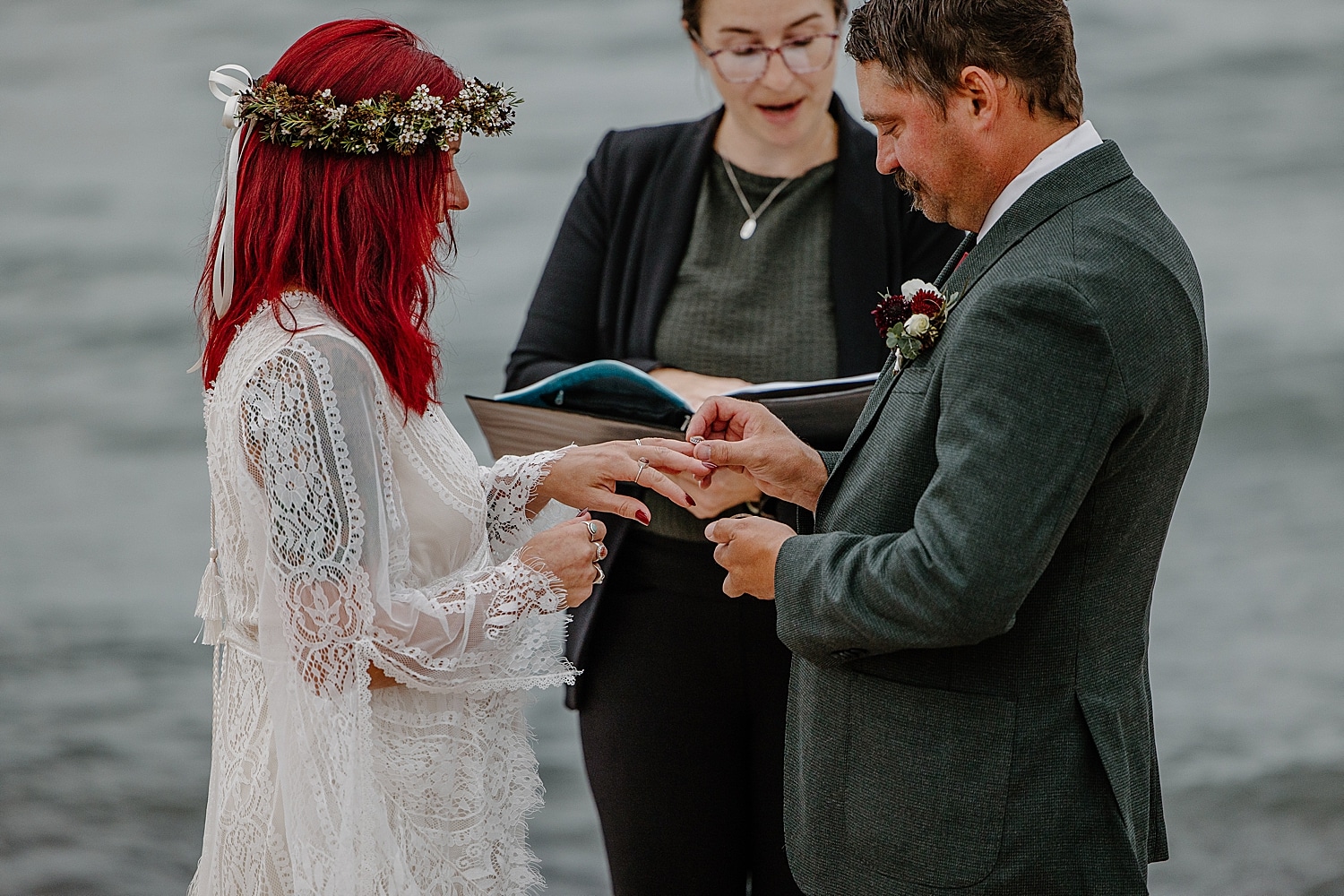 husband and wife exchange rings near water for Wisconsin Beach Elopement