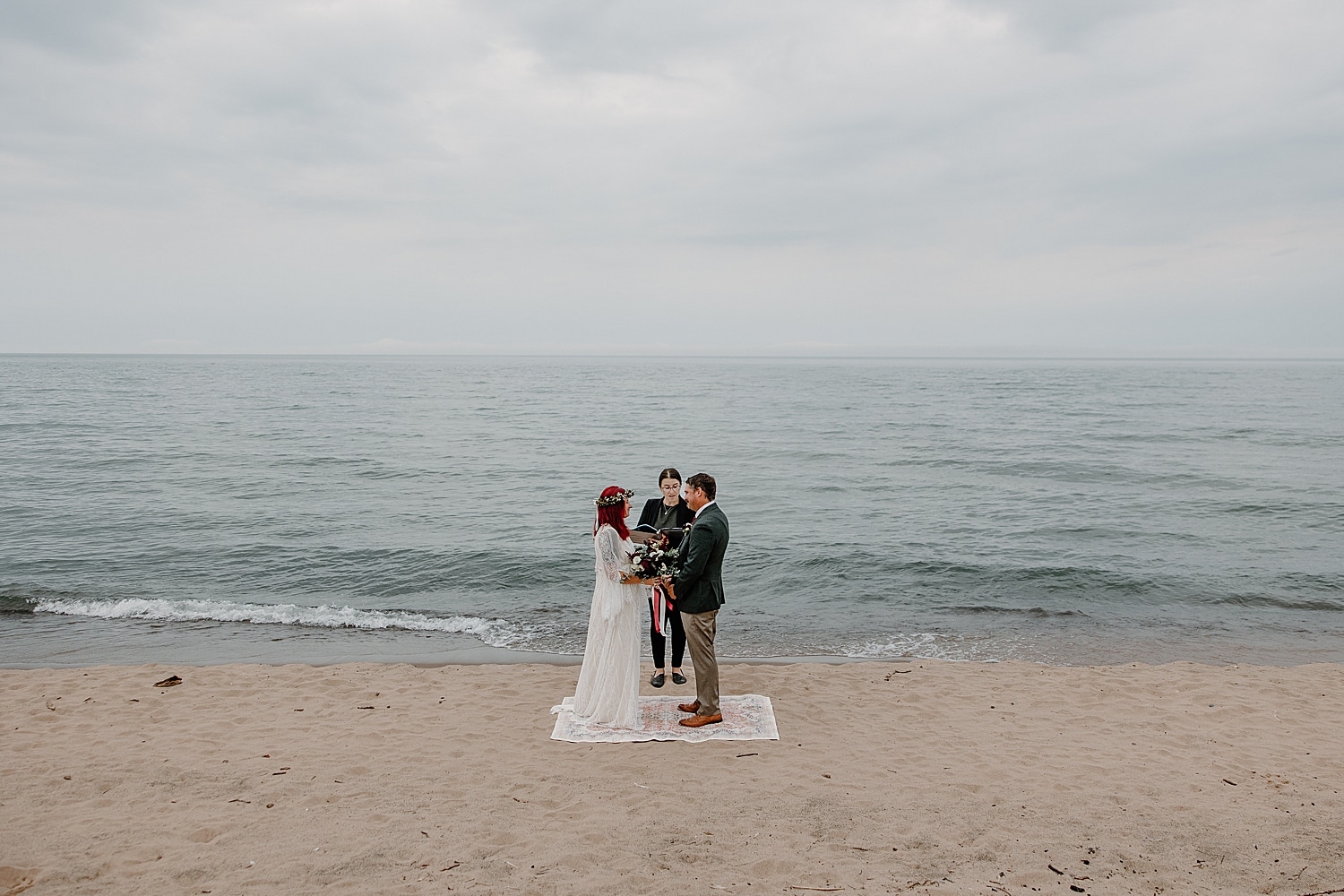 newlyweds stand on rug near the water for Wisconsin Beach Elopement
