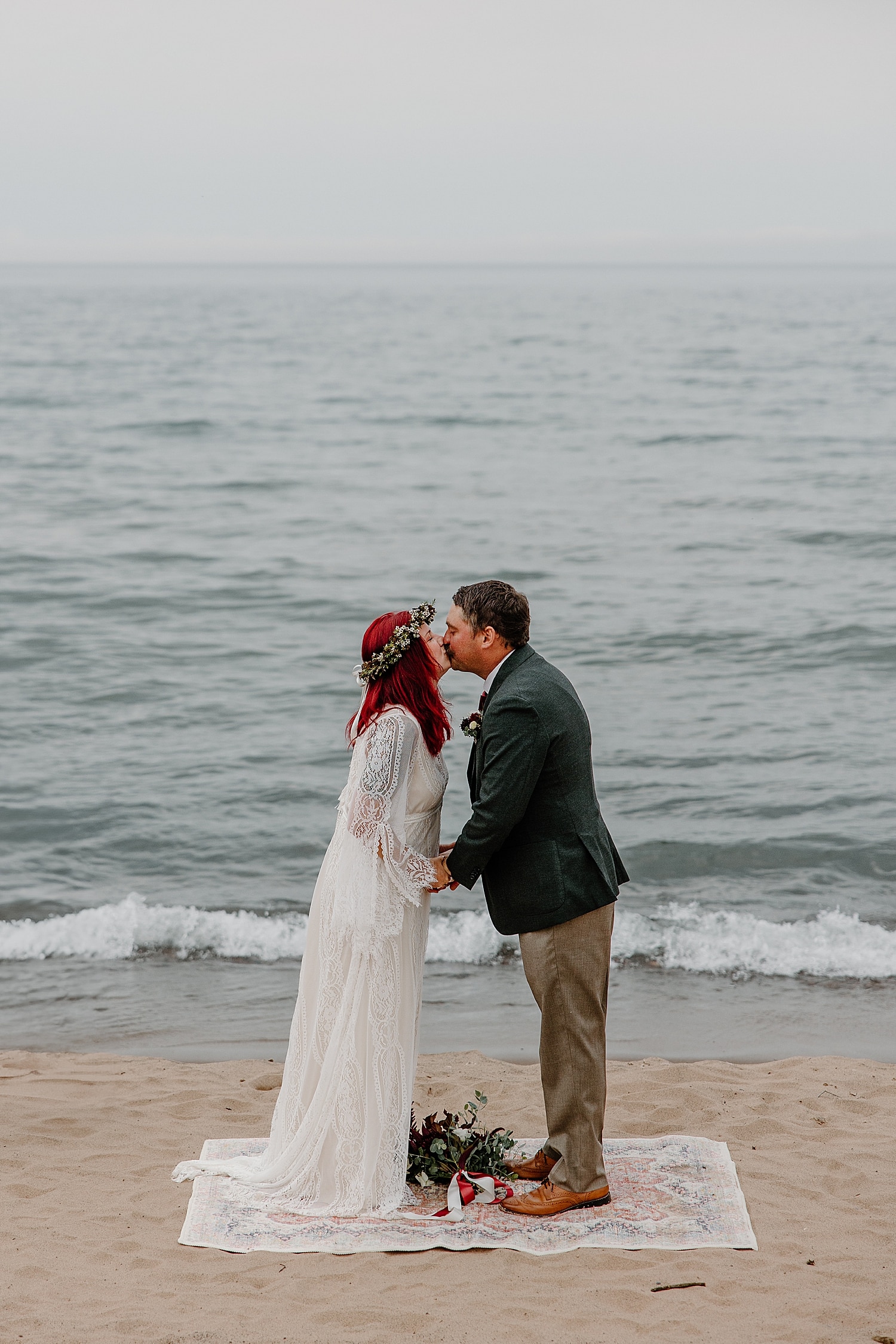 man leans in to kiss his new bride on the sand for Wisconsin Beach Elopement