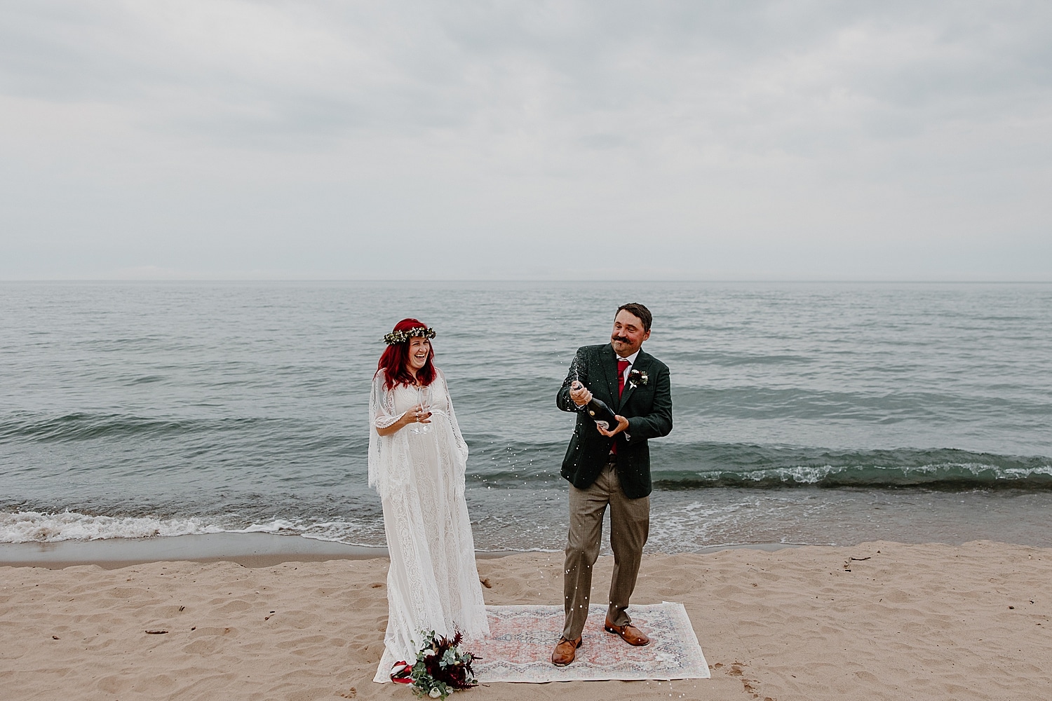 newlyweds pop champagne after saying I Do near water by Minnesota wedding photographer