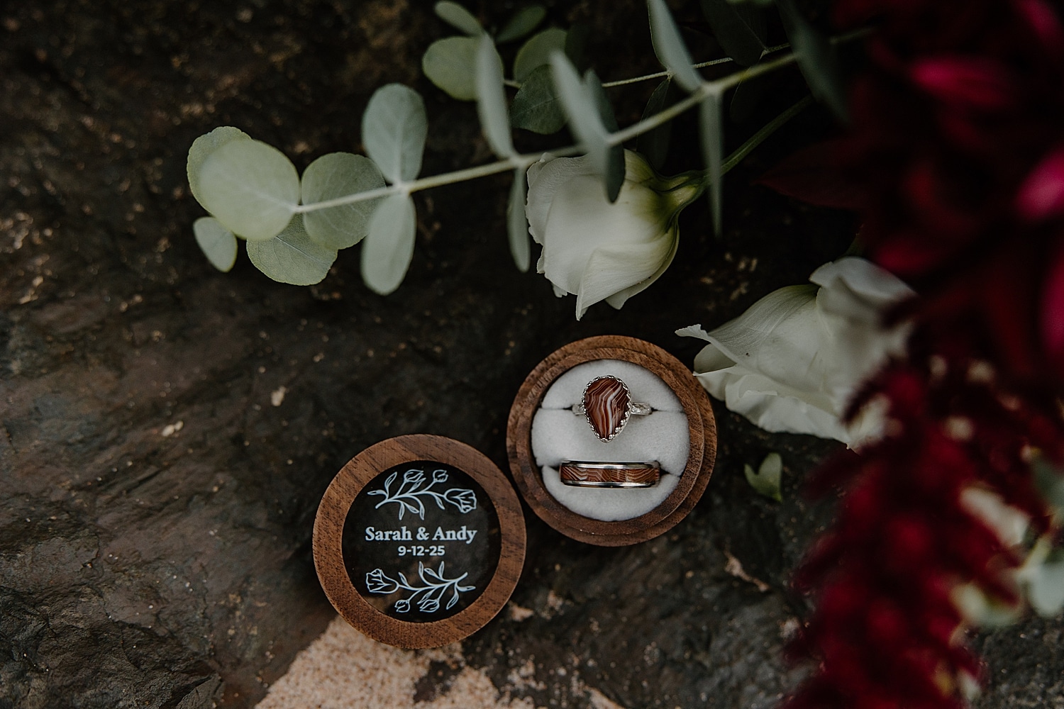 rings sit in wooden box on sand by Samantha Burke Photography