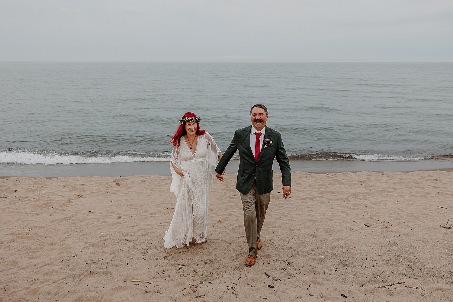 groom with red tie walks with bride up the sand for Wisconsin Beach Elopement