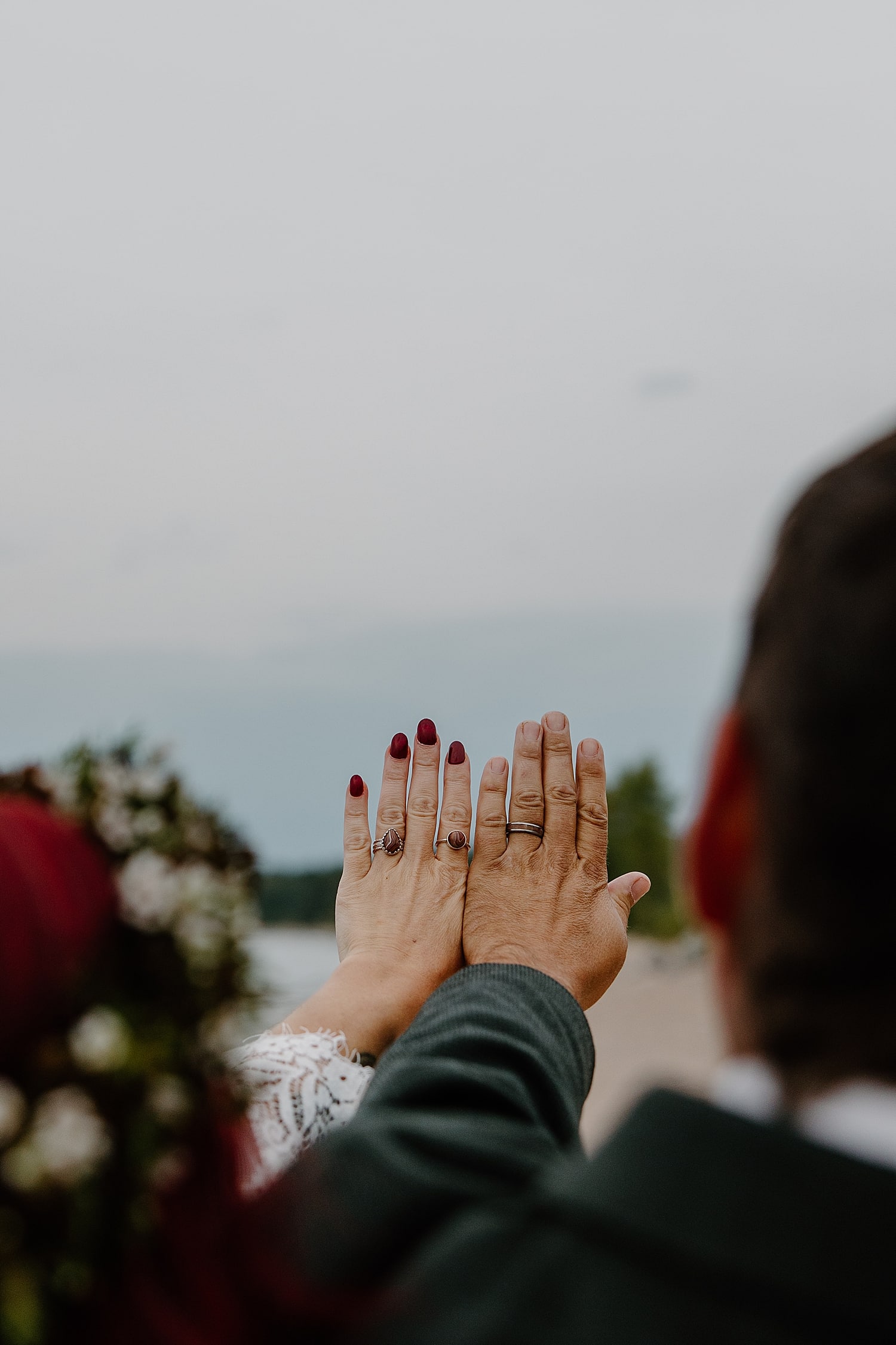husband and wife hold up hands to show off new rings for Wisconsin Beach Elopement