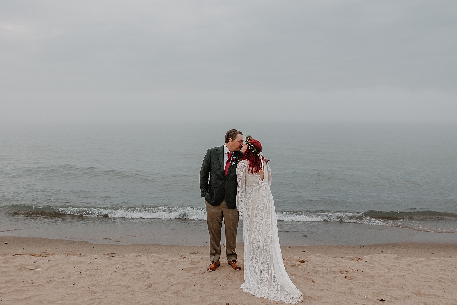 husband and wife share a kiss in front of water by Minnesota wedding photographer