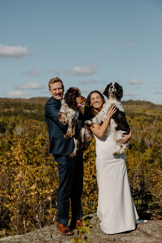 newlyweds hold up their large dogs after saying I Do showing how to include pets in your elopement