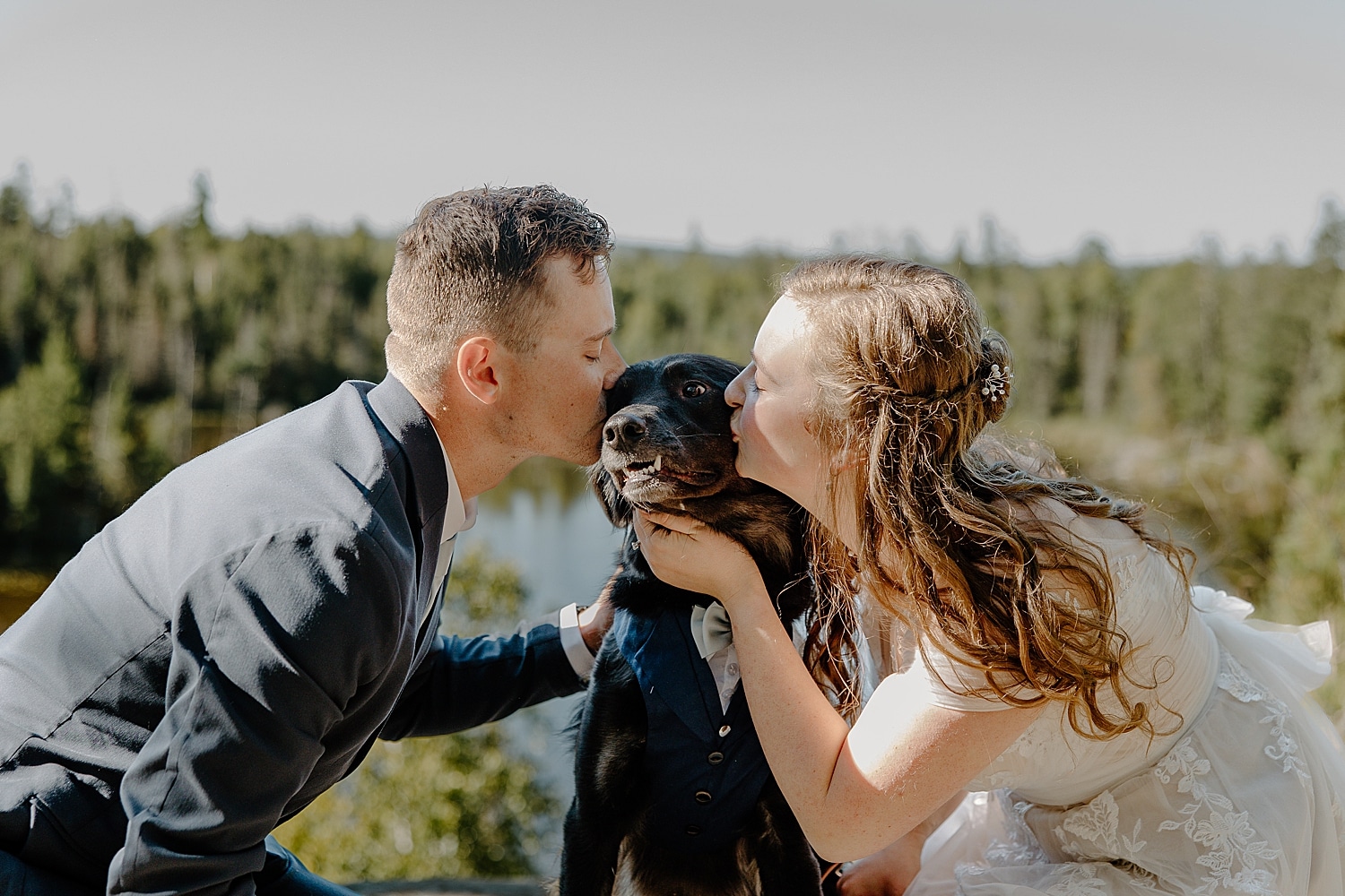 husband and wife lean in to kiss their mutt by Samantha Burke Photography