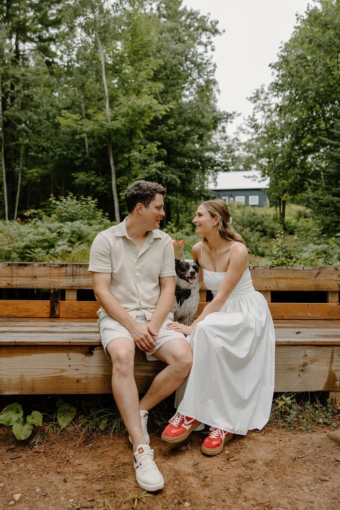 young couple sits on bench with their pet between them by Wisconsin wedding photographer
