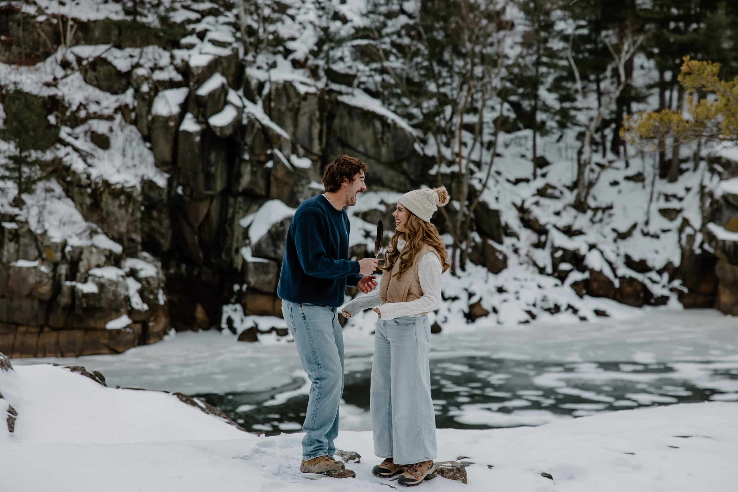 husband and wife to be stand in front of frozen lake by Wisconsin wedding photographer