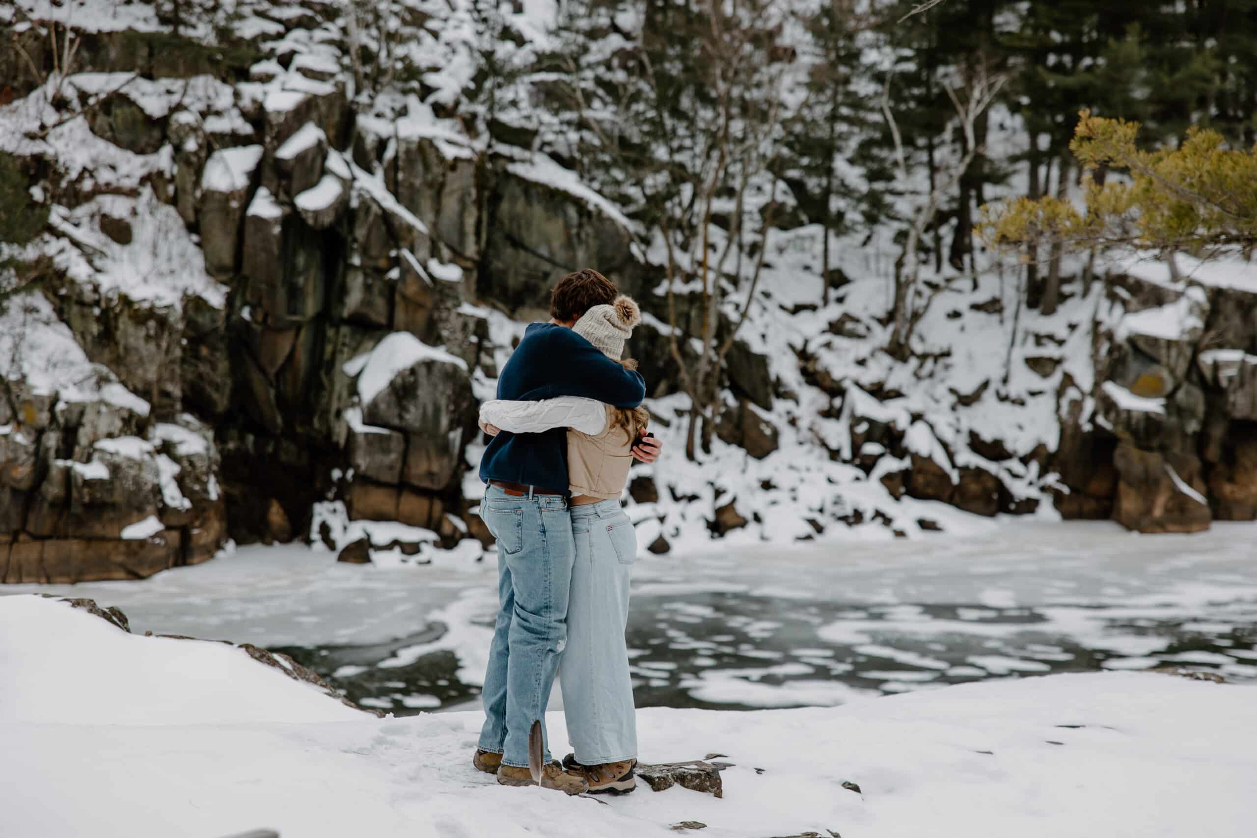 newly engaged couple hugs tightly in front of frozen water by Samantha Burke Photography