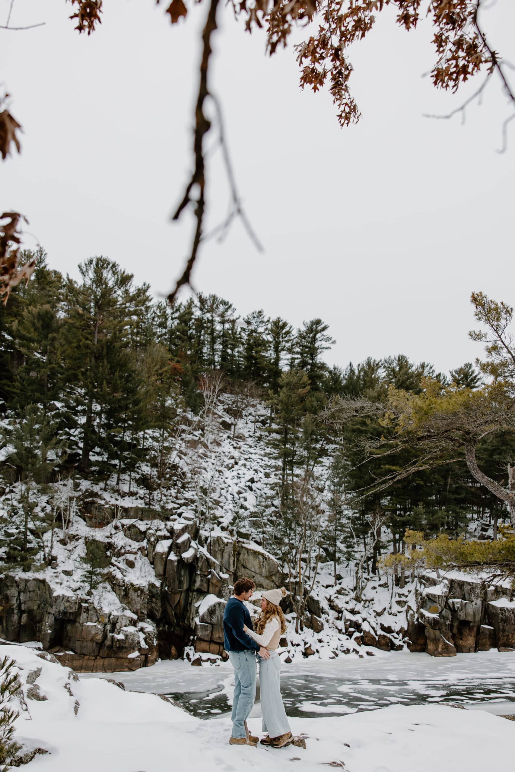 newly engaged couple stands in front of snowy mountain by Wisconsin wedding photographer