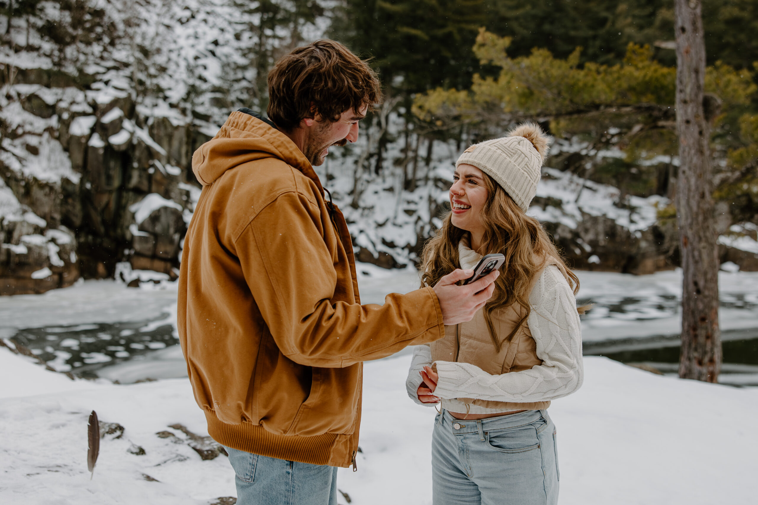 man shows wife-to-be something on his phone by Samantha Burke Photography