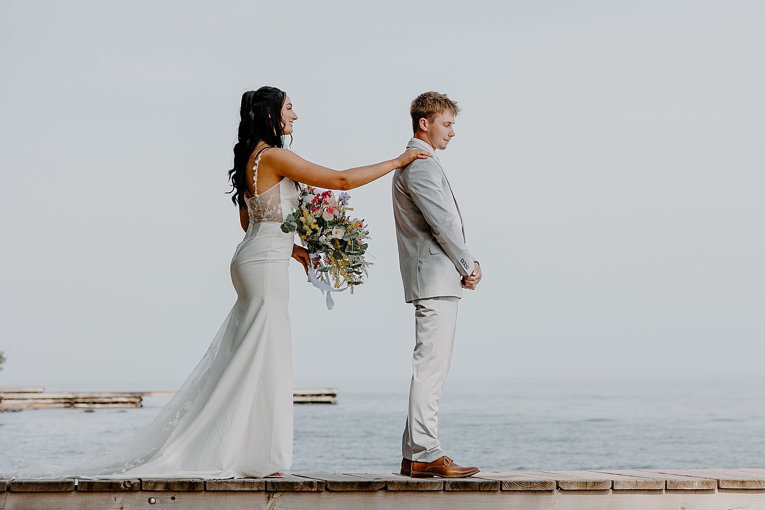 woman approaches man on dock for first look by Minnesota elopement photographer