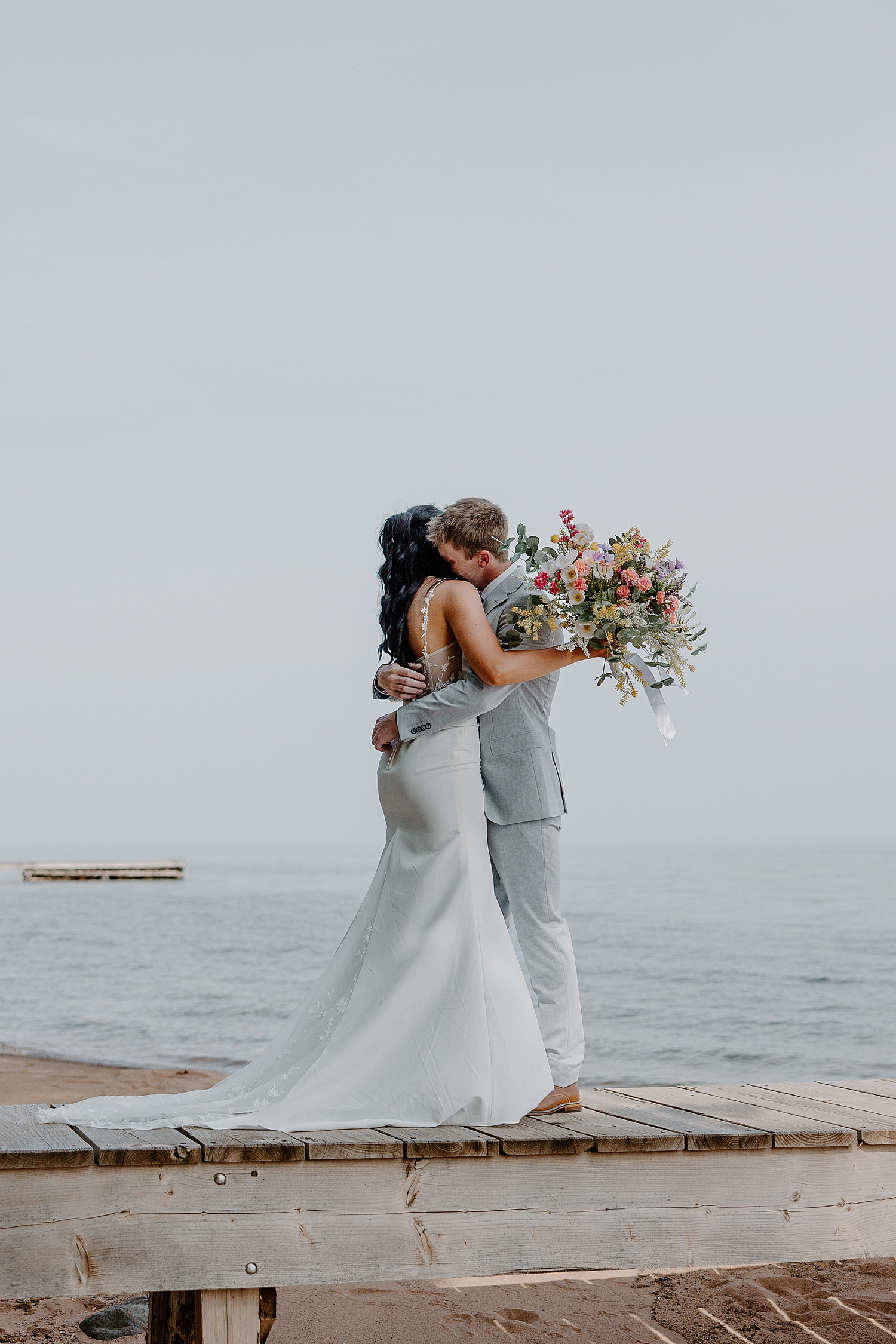 man hugs his wife on dock by Samantha Burke Photography