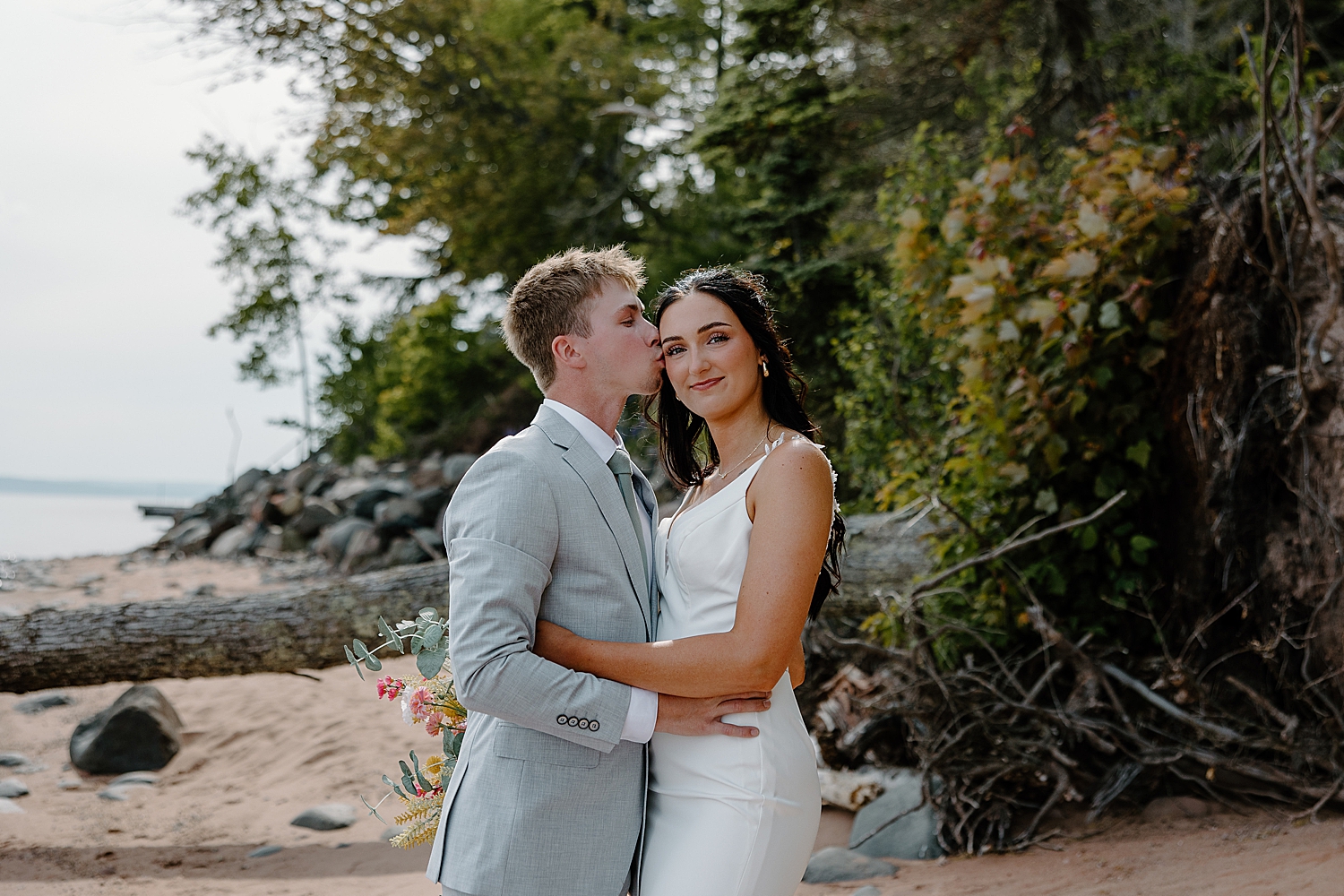 brunette bride smiles as groom kisses her temple by Minnesota elopement photographer