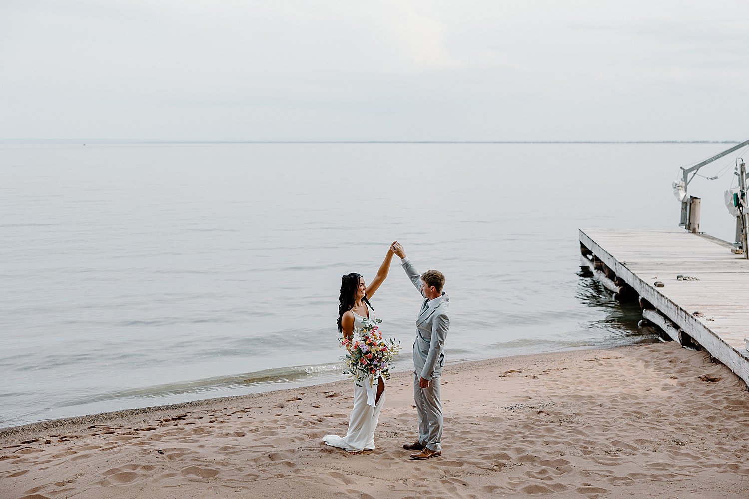 man spins his bride-to-be next to water by Minnesota elopement photographer