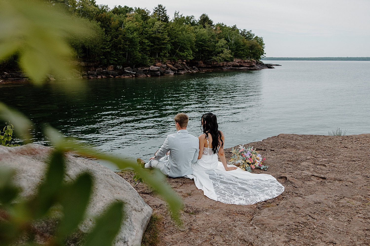 husband and wife sit on cliff edge together by Samantha Burke Photography