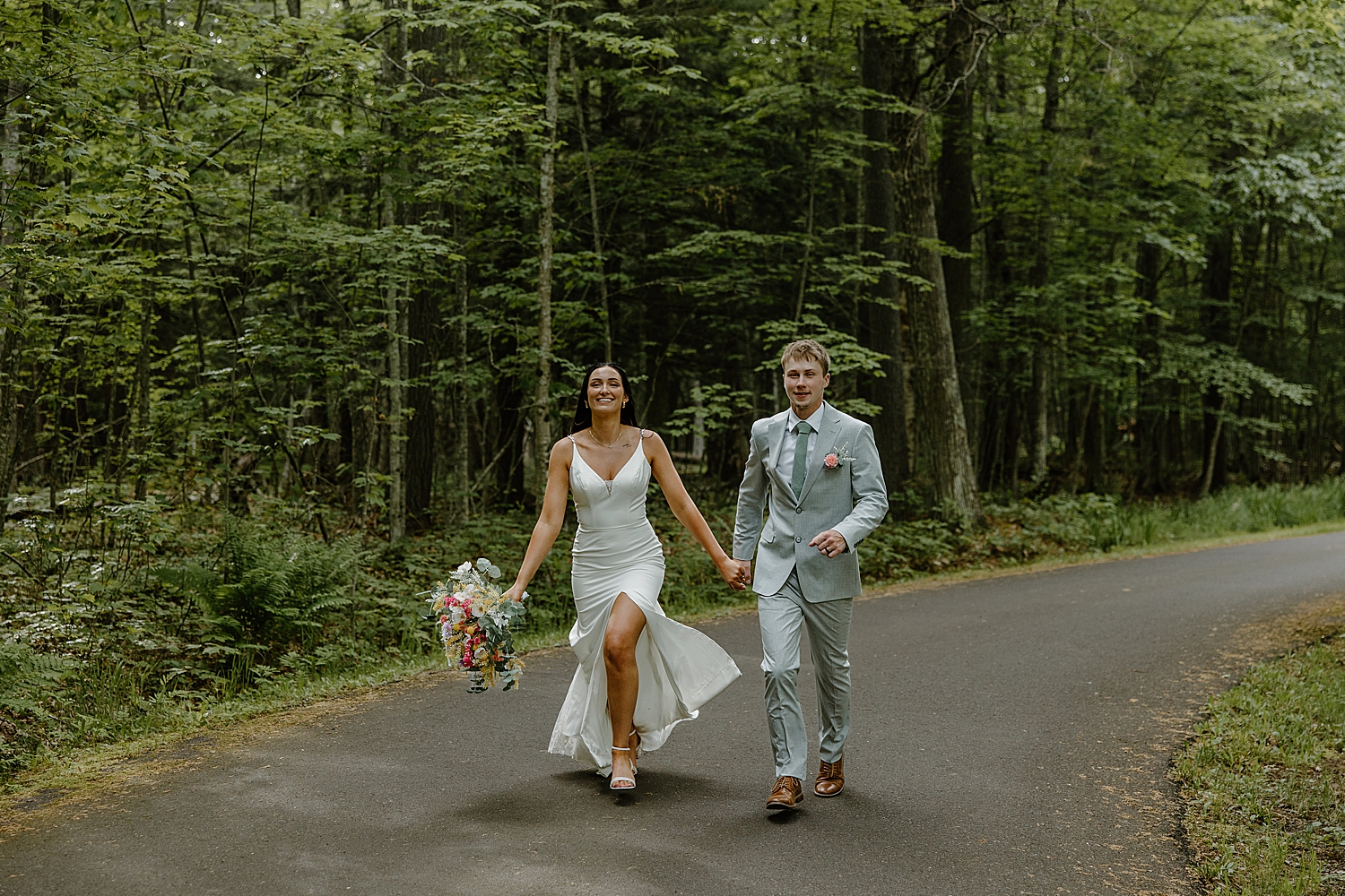newlyweds skip down the forest path for Lake Superior intimate wedding