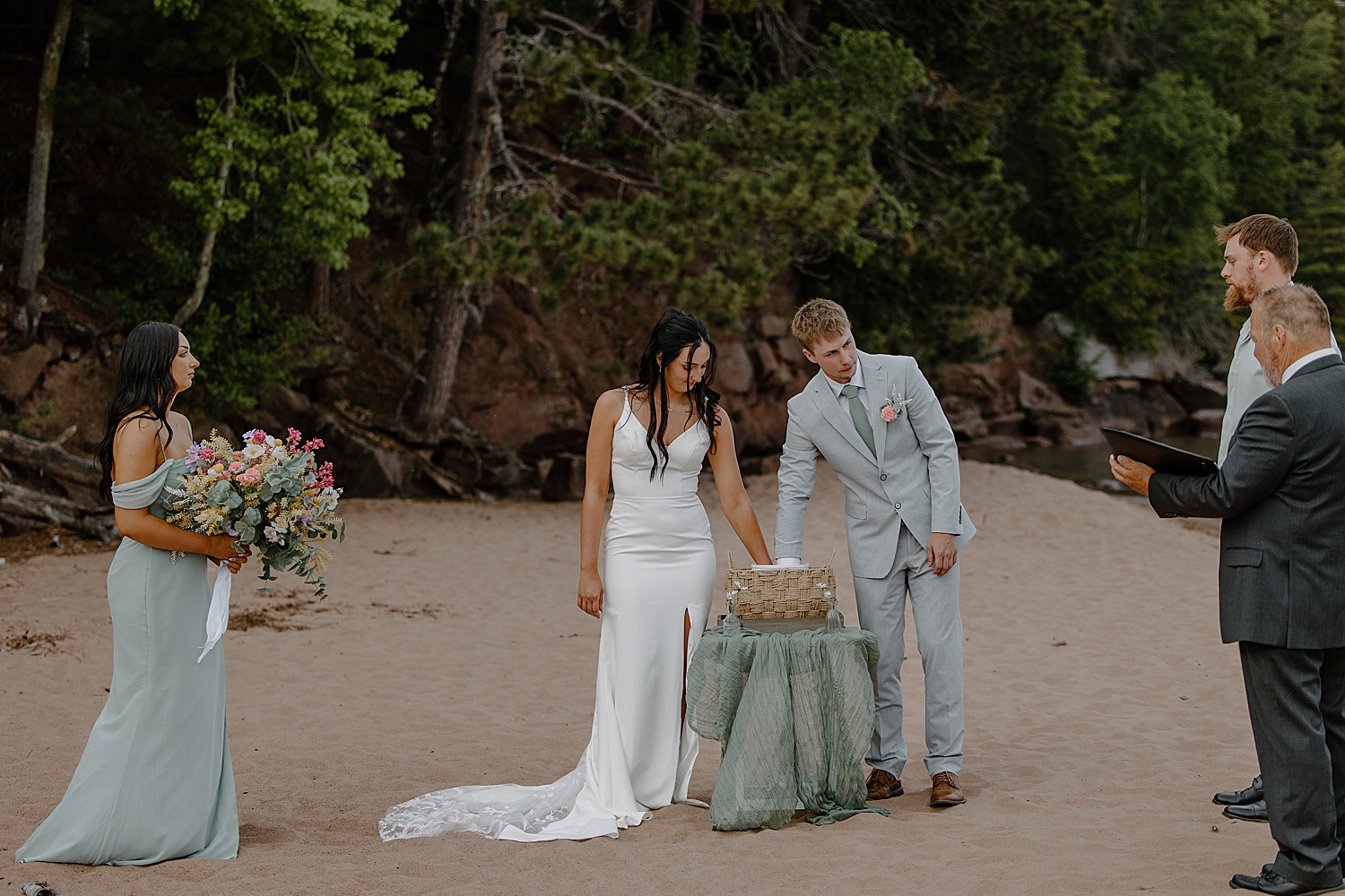 newlyweds do a hand mold on the beach by Minnesota elopement photographer